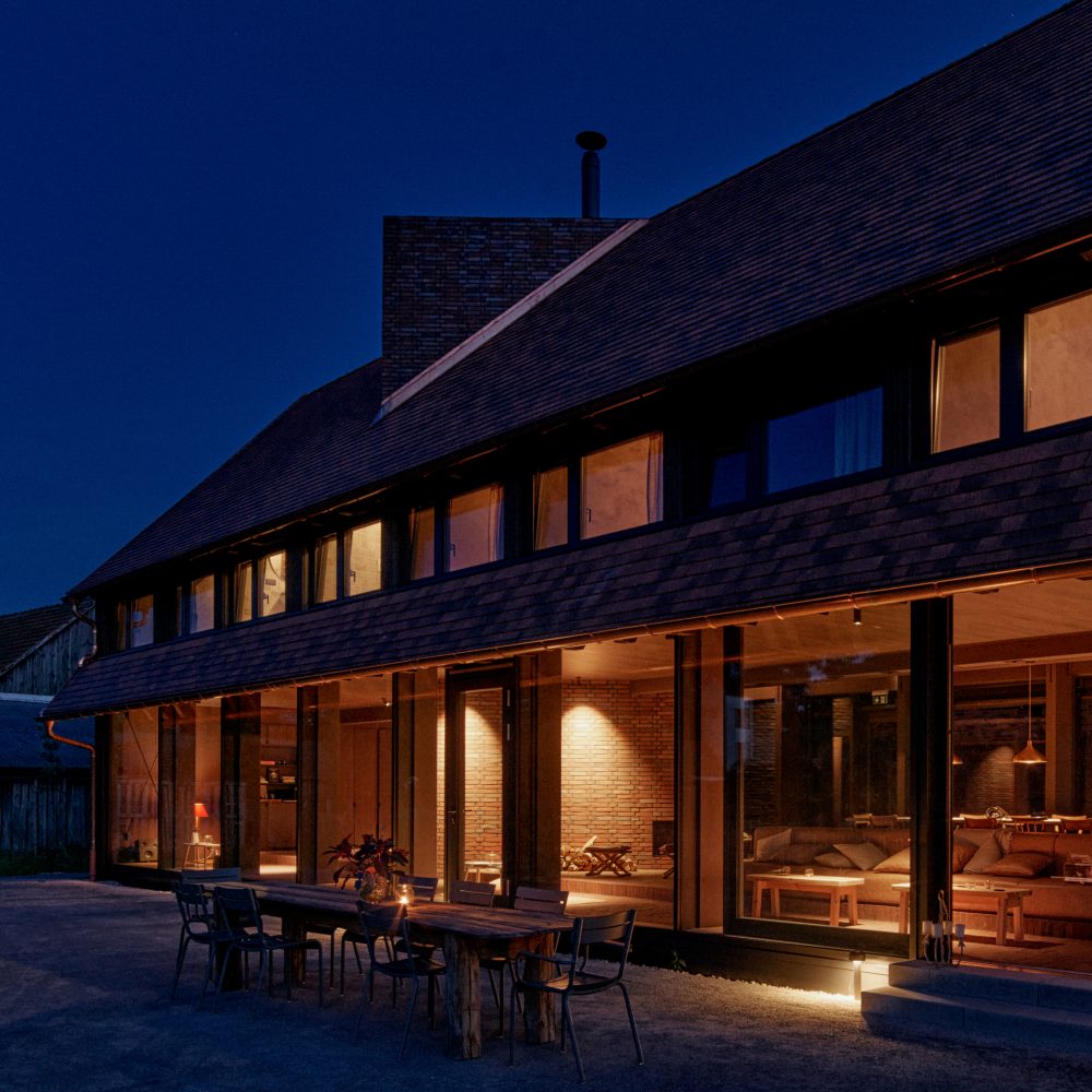 Moderne Scheune der Michelberger Farm am Abend mit Lobby und gemütlichem Licht